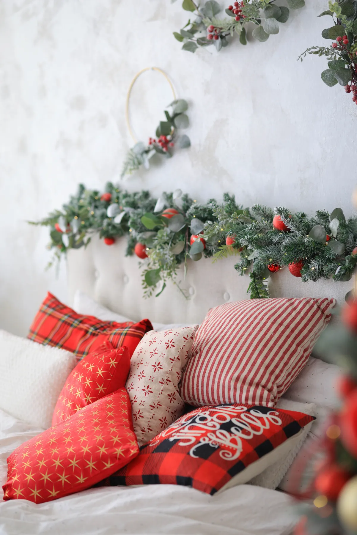 A beautifully decorated bedroom with Christmas-themed pillows and greenery.