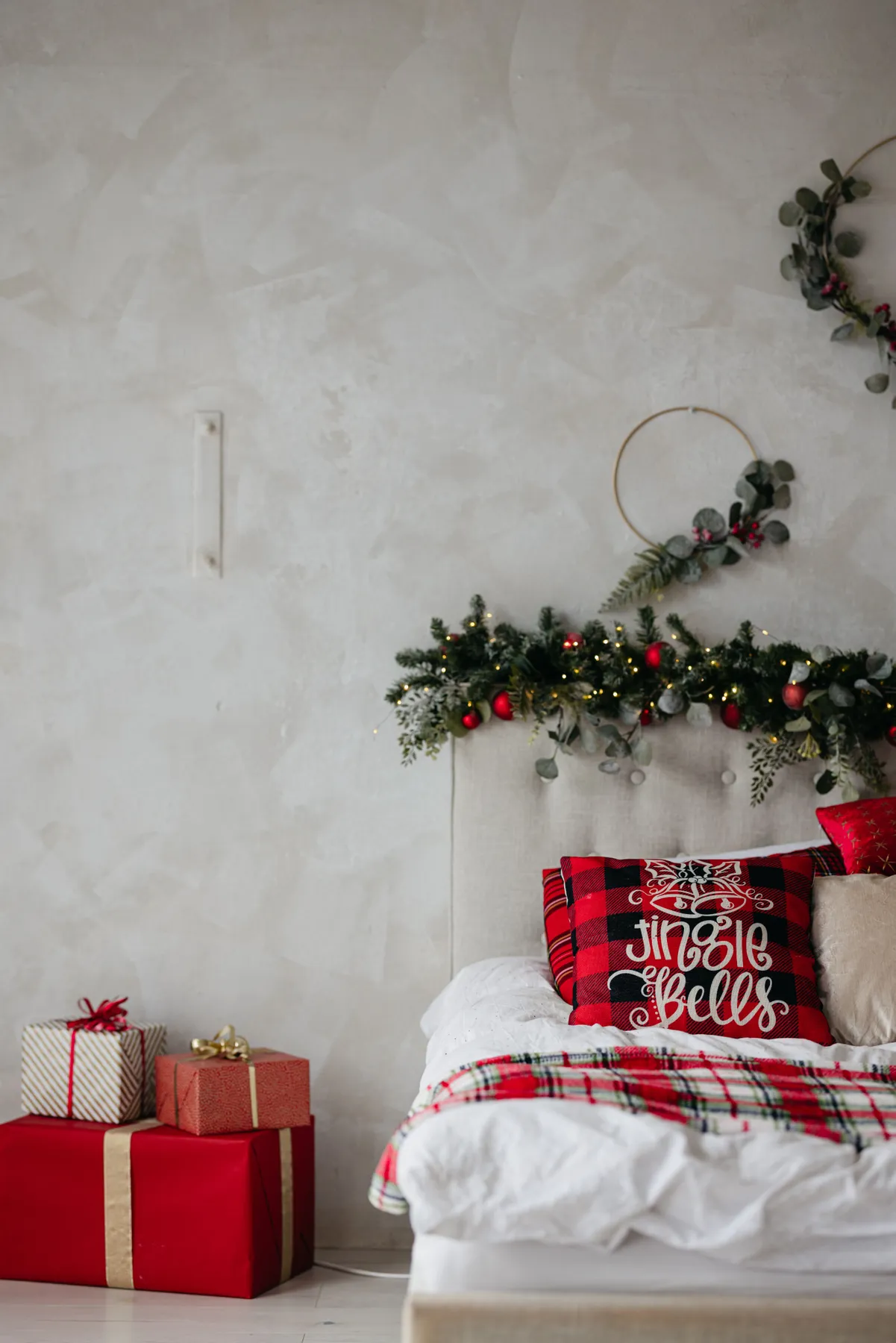 A festive bedroom with Christmas decorations, including a red pillow with 'Jingle Bells' text and gifts.