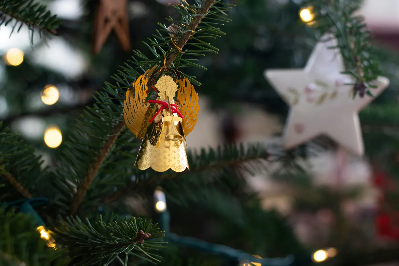 A little brass angel ornament complete with a red bow and trumpet.