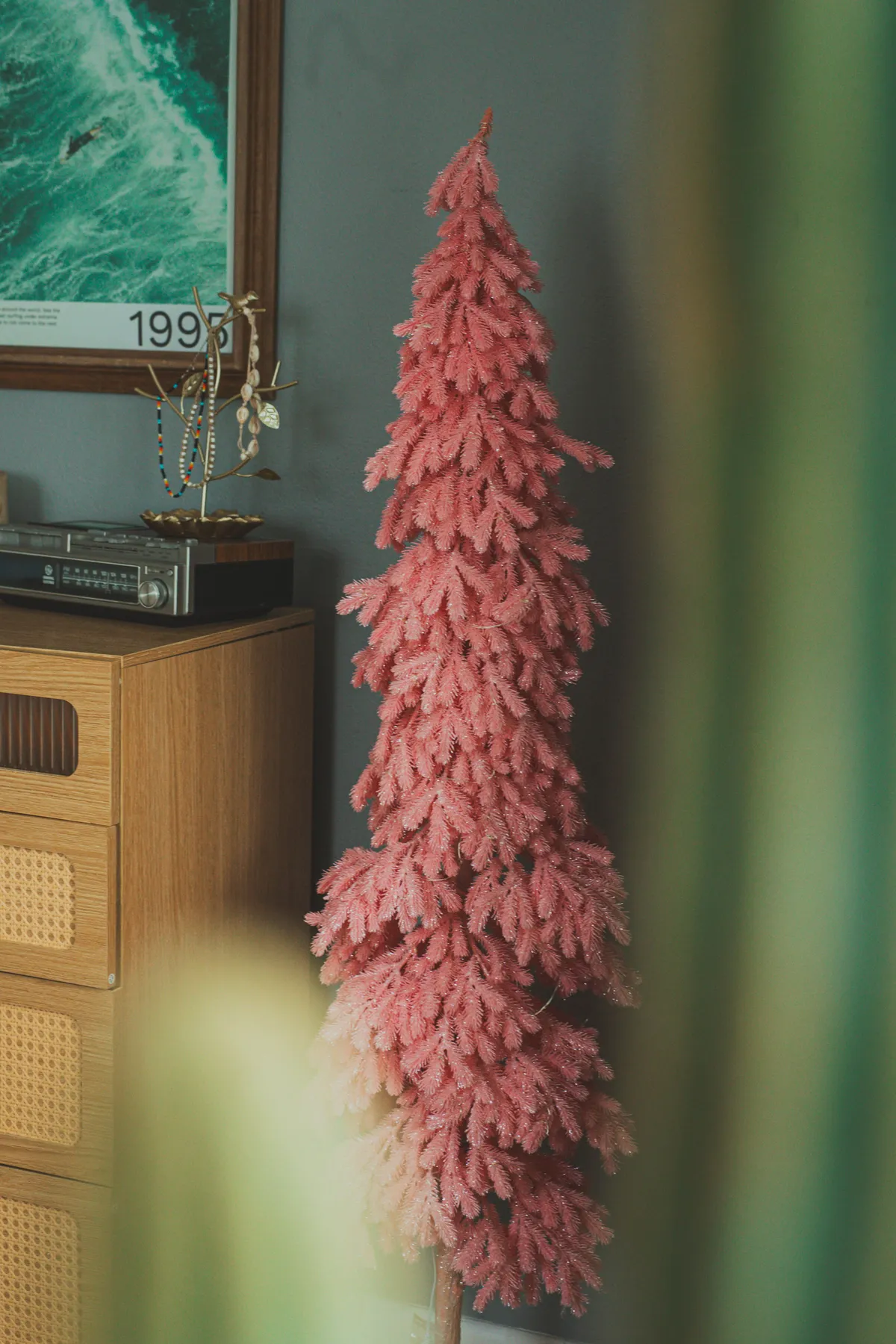 A vibrant pink Christmas tree stands elegantly in a vintage-style living room setting, adding a whimsical touch.
