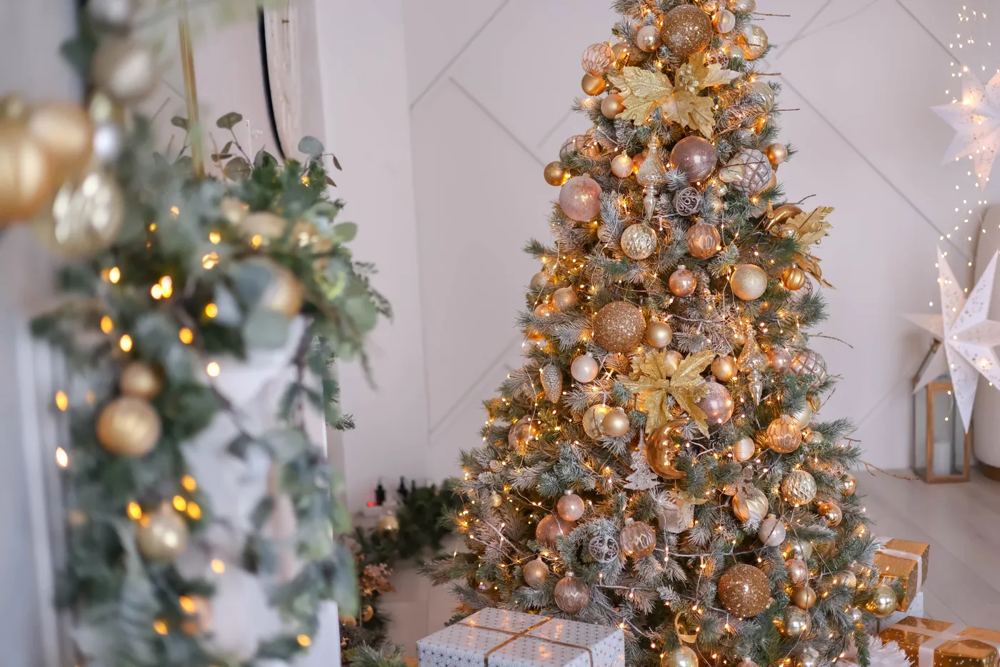 Beautifully decorated Christmas tree with lights and golden baubles in a cozy living room.