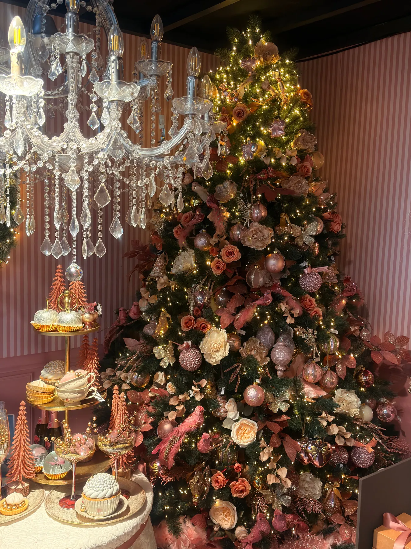 Beautifully decorated Christmas tree with a crystal chandelier and festive pastries.