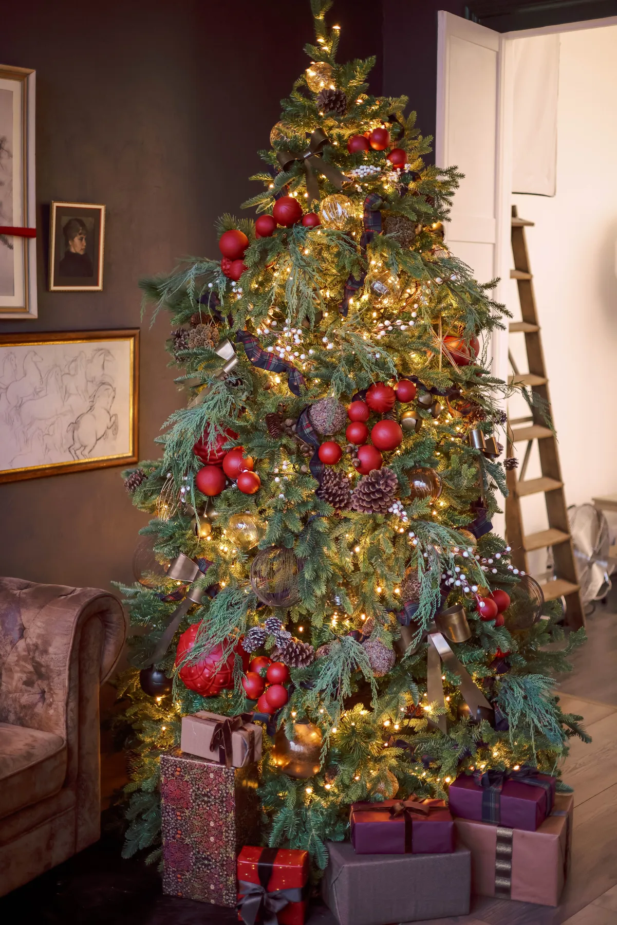 Beautifully decorated Christmas tree with lights and gifts indoors, perfect for the holiday season.