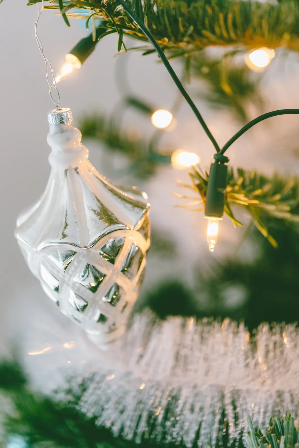 Close-up of a decorative ornament on a Christmas tree with lights sparkling around it.