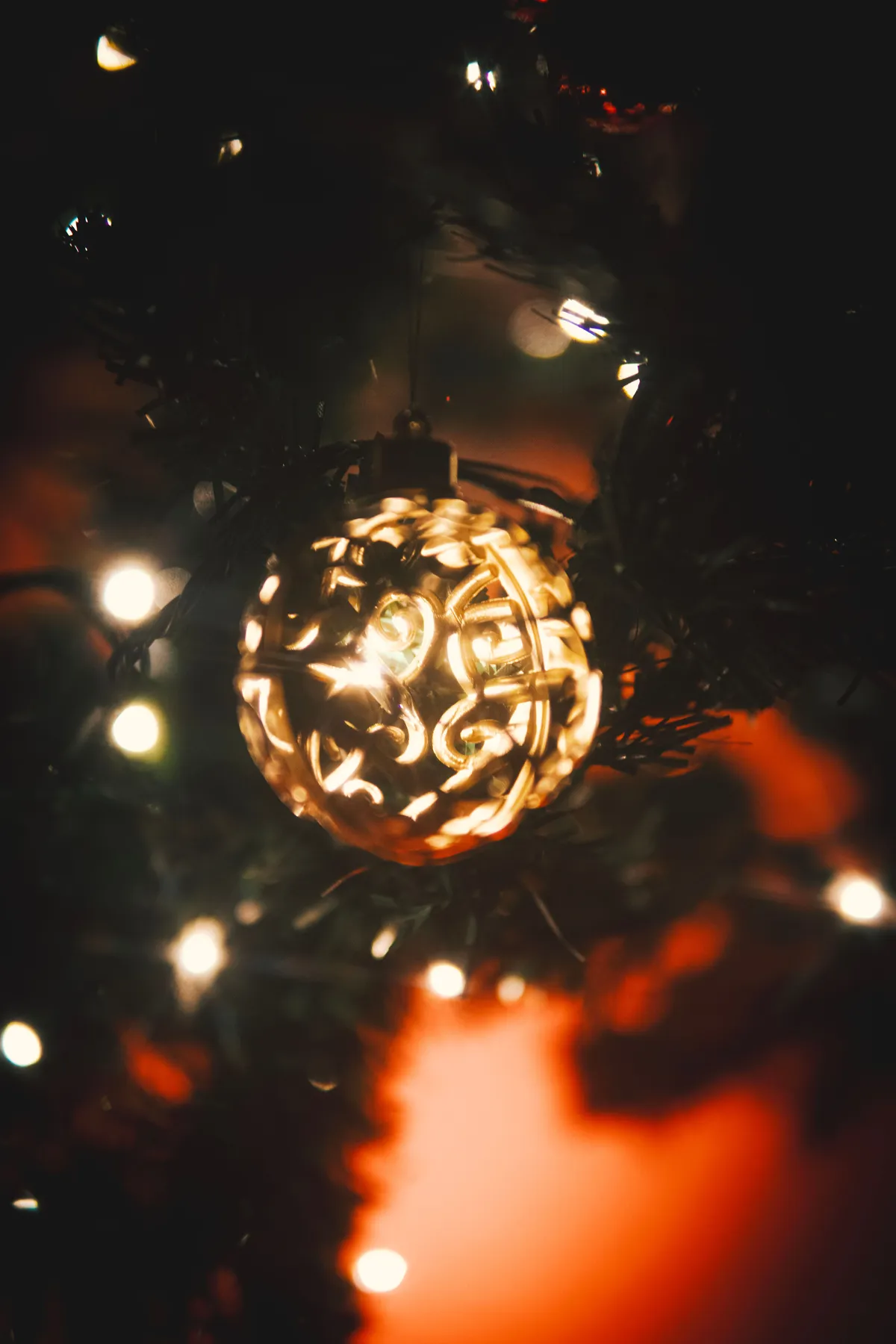Close-up of an illuminated Christmas ornament on a tree, creating a warm festive glow.