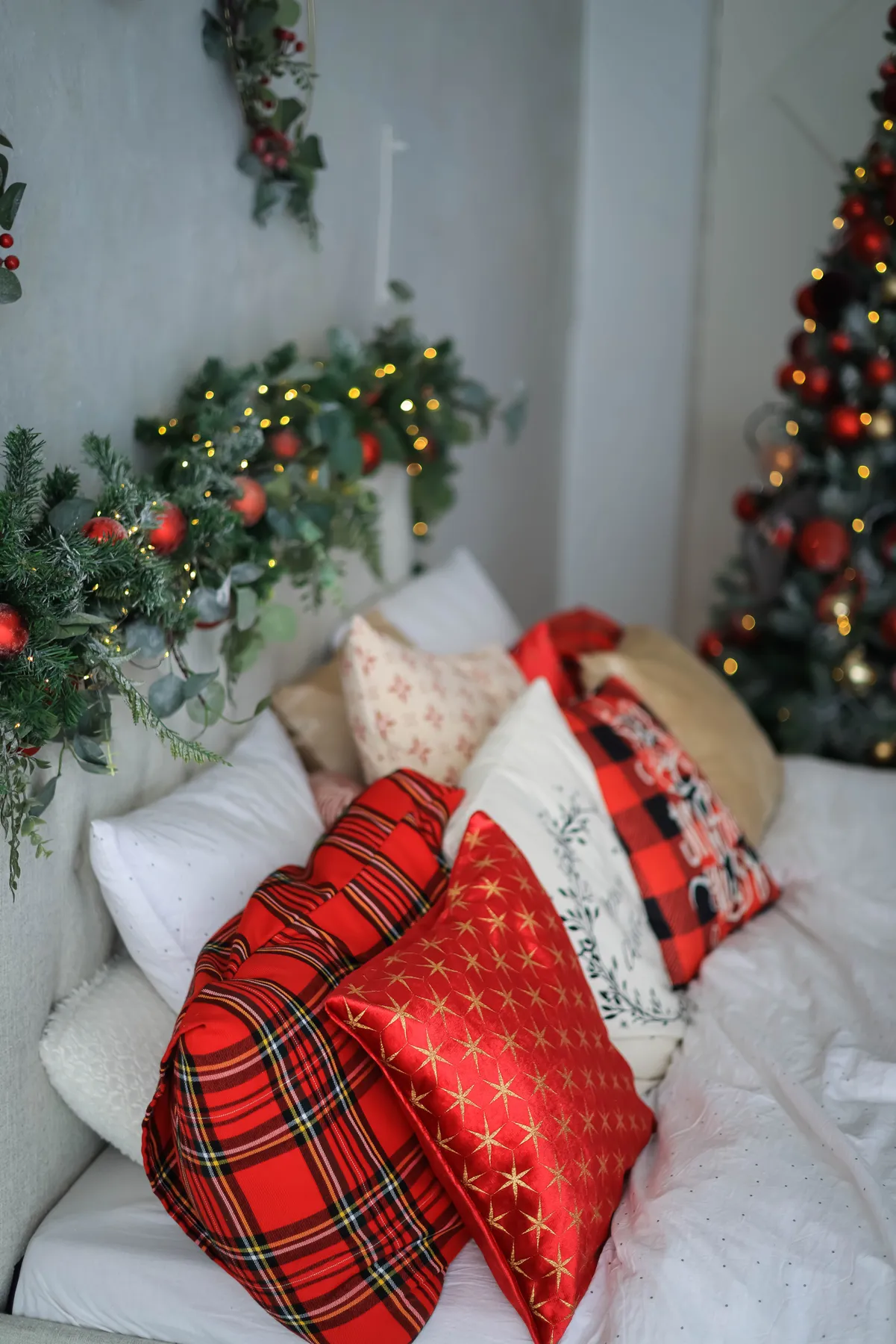 Cozy Christmas-themed bedroom with decorative pillows and festive garlands.