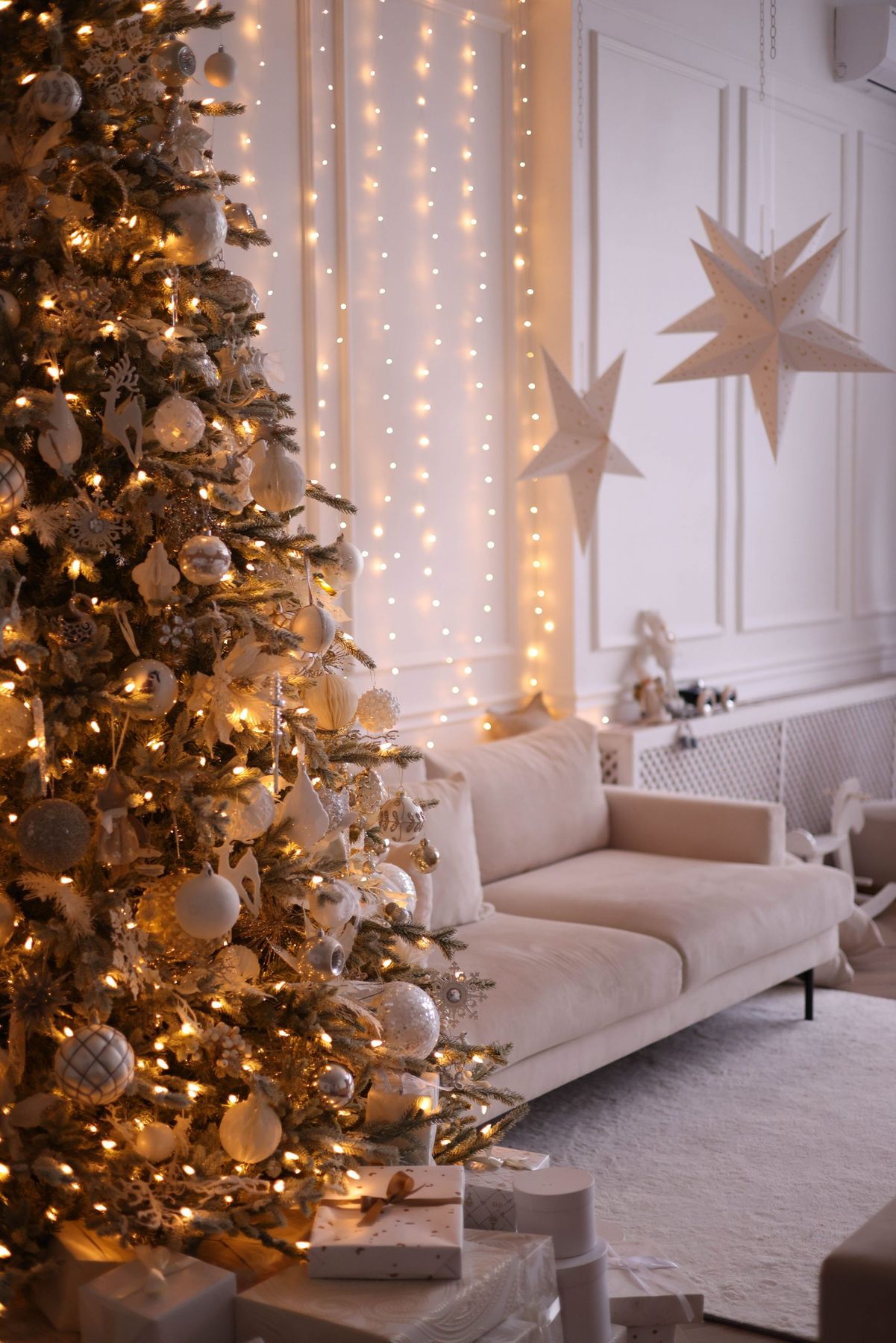 Cozy living room featuring a beautifully decorated Christmas tree with lights and gifts.