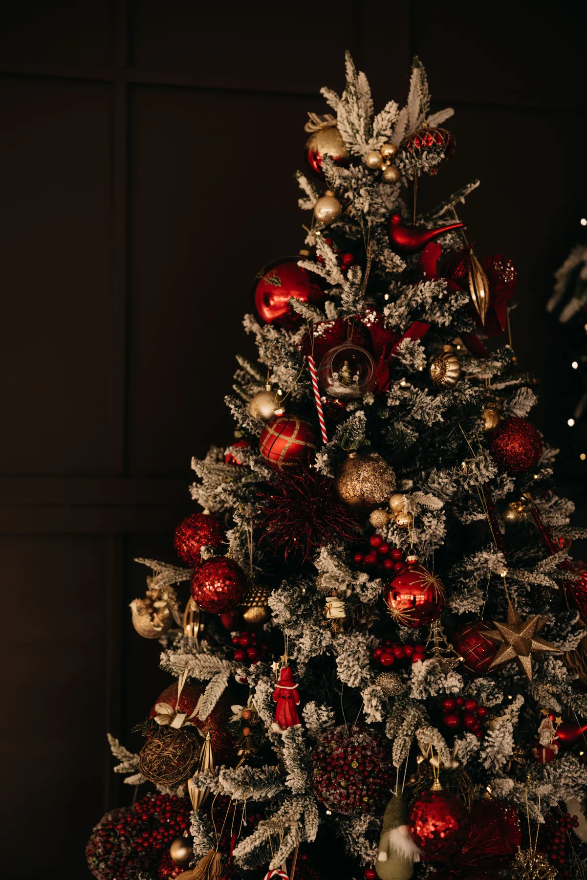 Festive Christmas tree adorned with red and gold ornaments, set in a cozy indoor atmosphere.