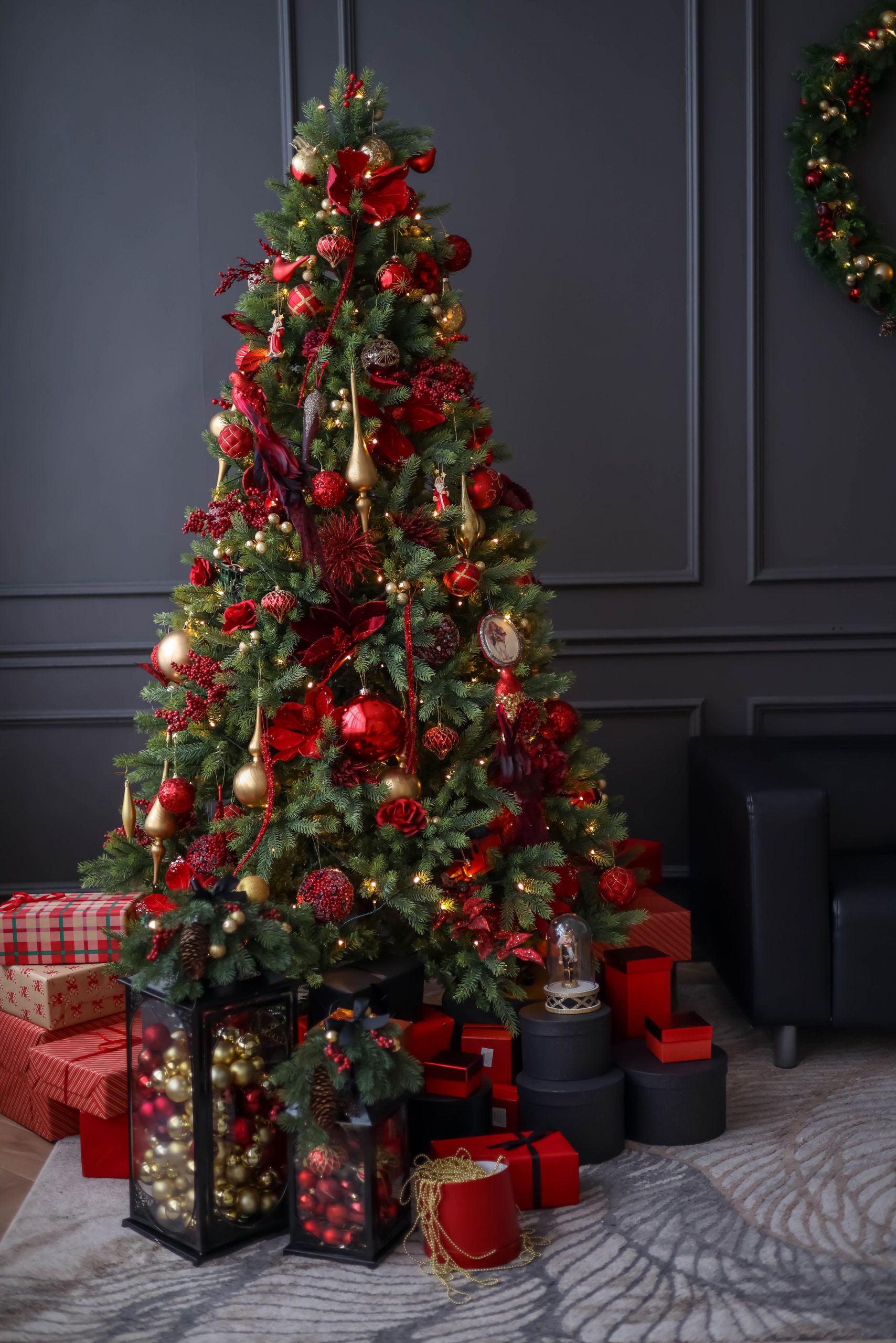 Festive Christmas tree with red and gold decorations in a cozy living room setting.