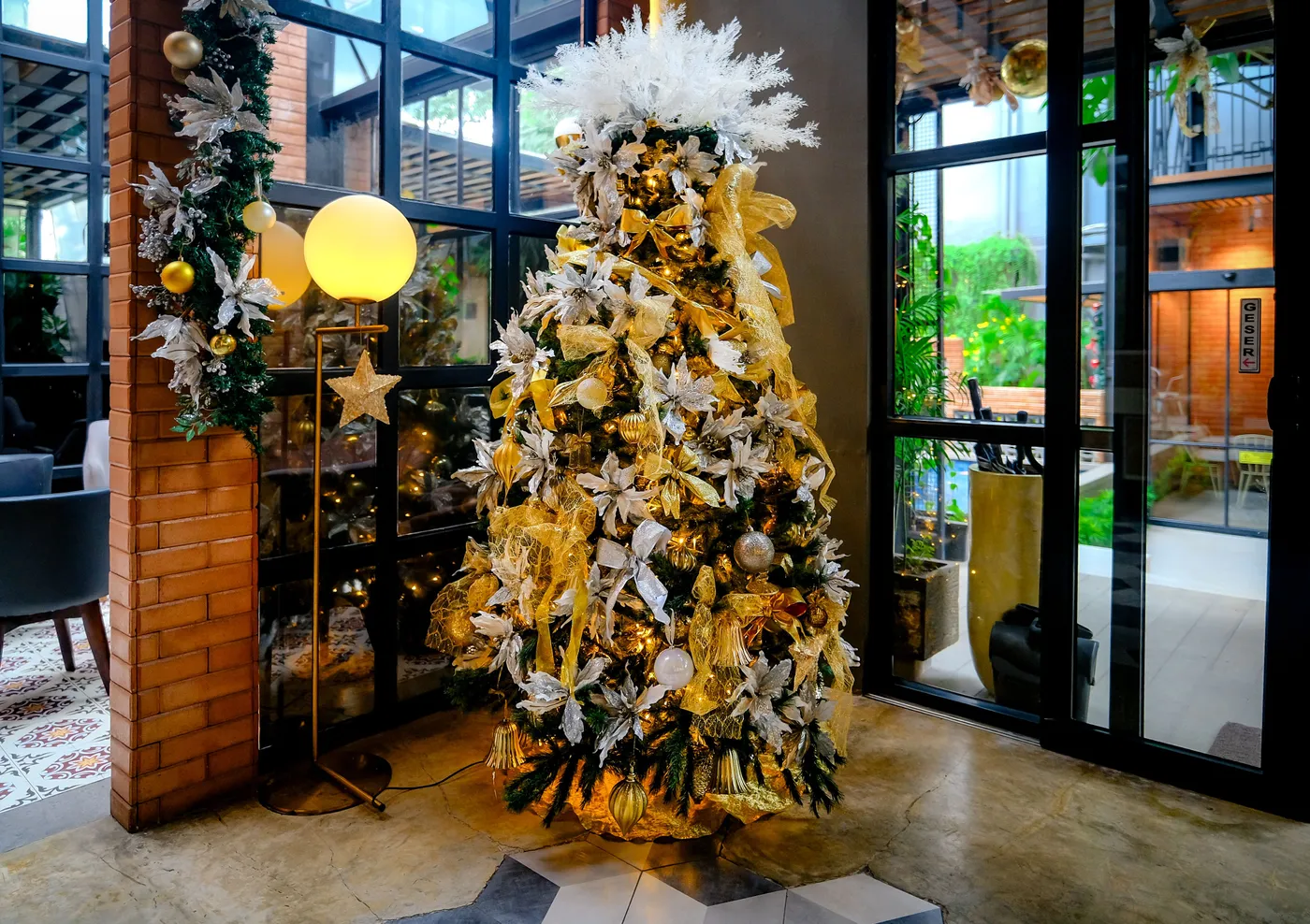 Luxurious Christmas tree adorned with gold and white ornaments in an indoor holiday setting.