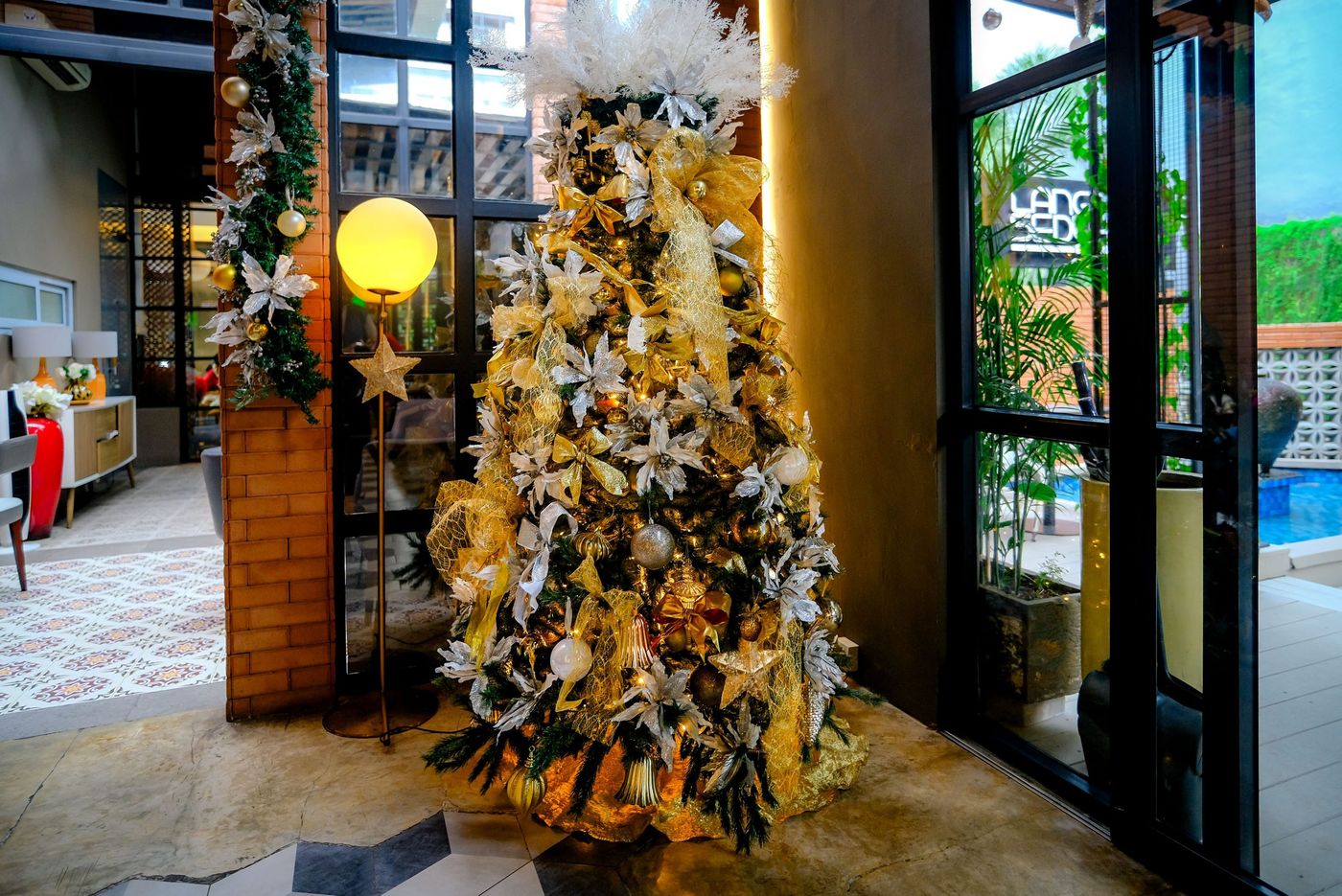 Luxurious Christmas tree with gold and white decor in a Jakarta hotel lobby.