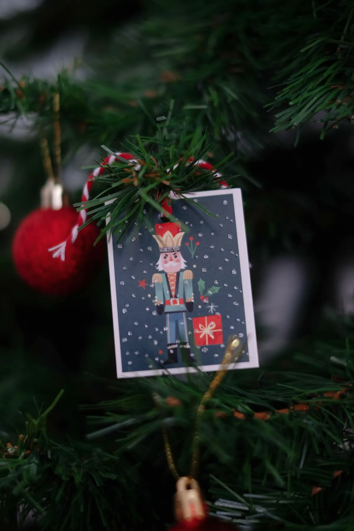 Nutcracker ornament and red bauble on a Christmas tree branch, creating a festive holiday ambiance.