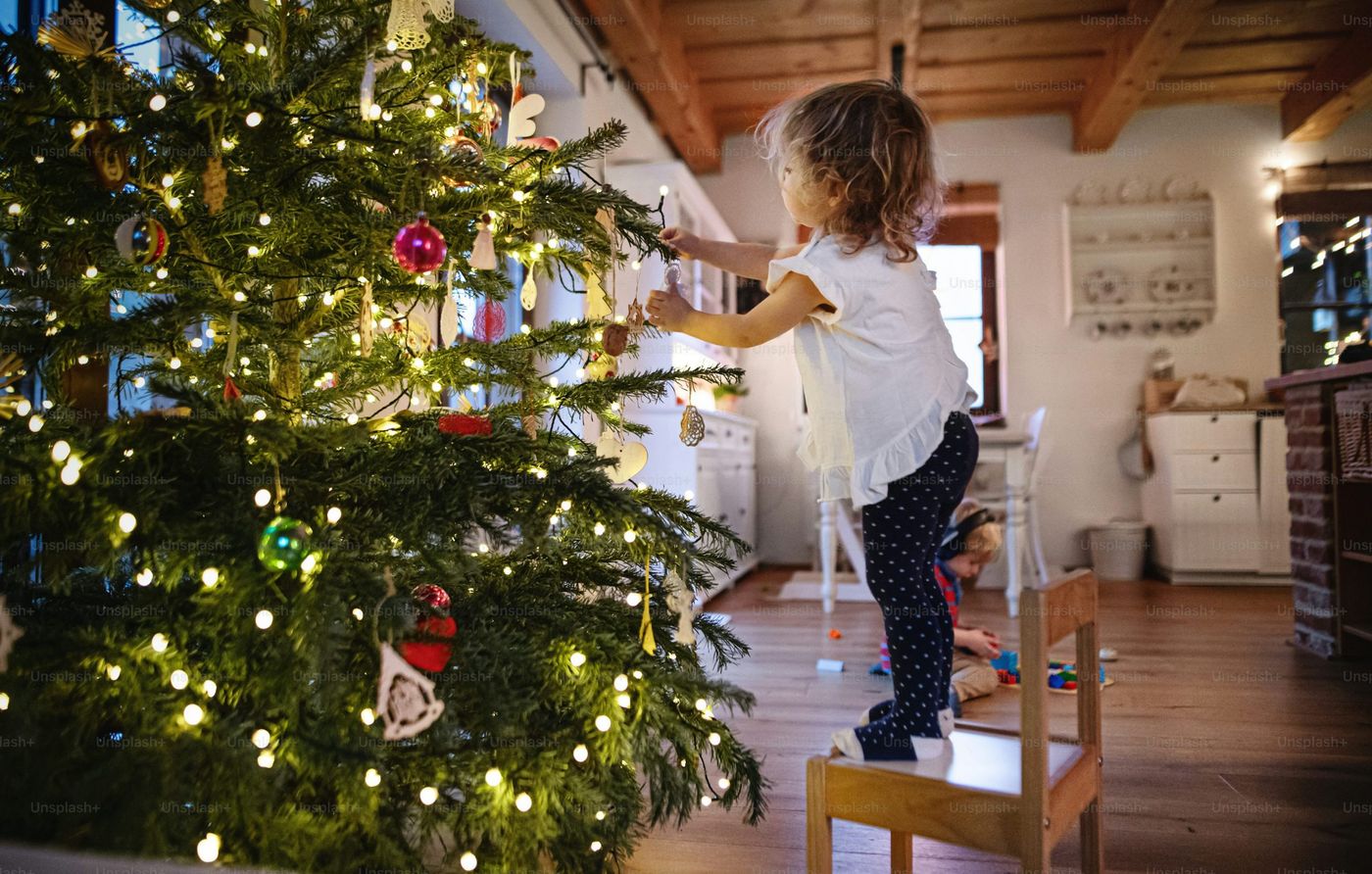 Side view portrait of small girl indoors at home at Christmas, decorating  tree - Photo on Unsplash+