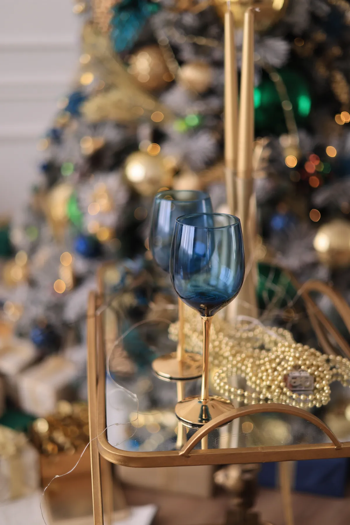 Sophisticated Christmas setting featuring blue wineglasses and festive decorations.