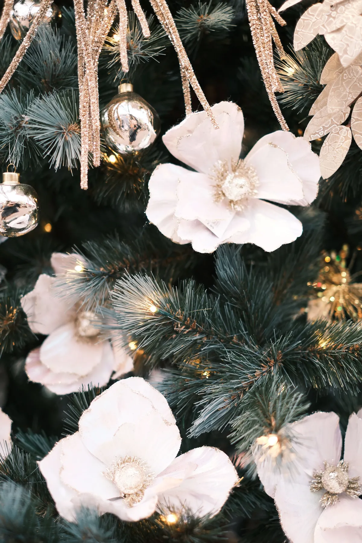 Sophisticated holiday decor with white flowers and lights on a Christmas tree.