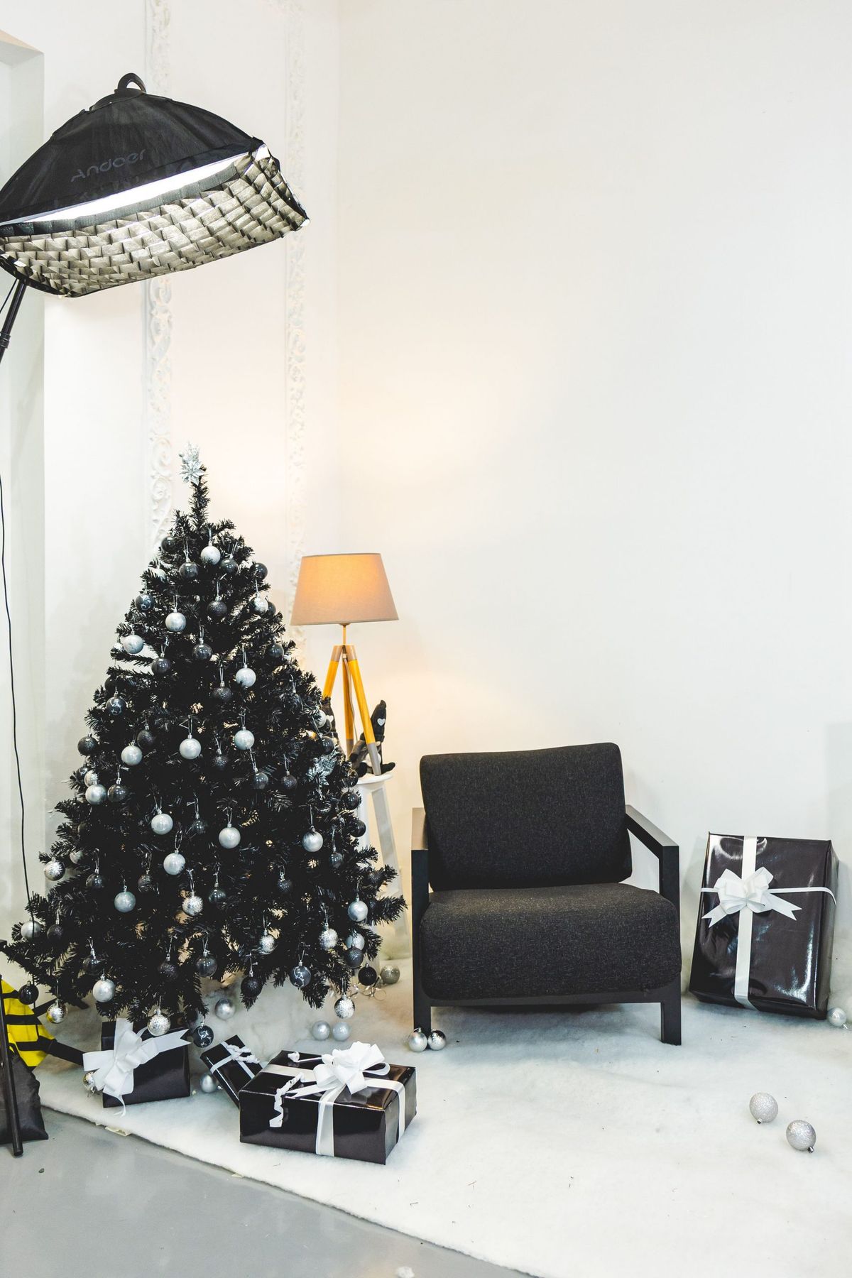 Stylish black Christmas tree with presents in a cozy modern room.
