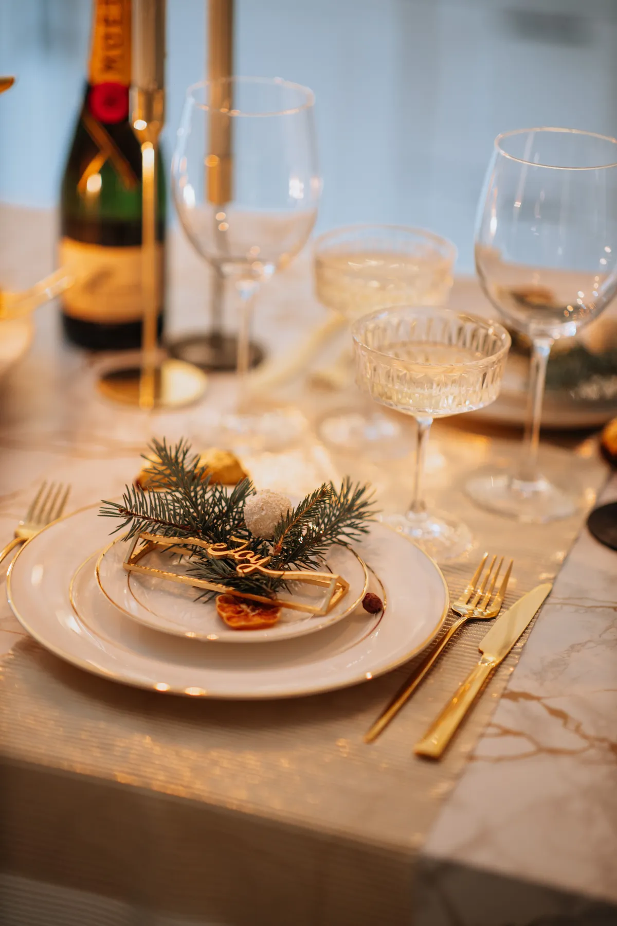 Stylish Christmas table setting with festive decorations, champagne, and golden accents.