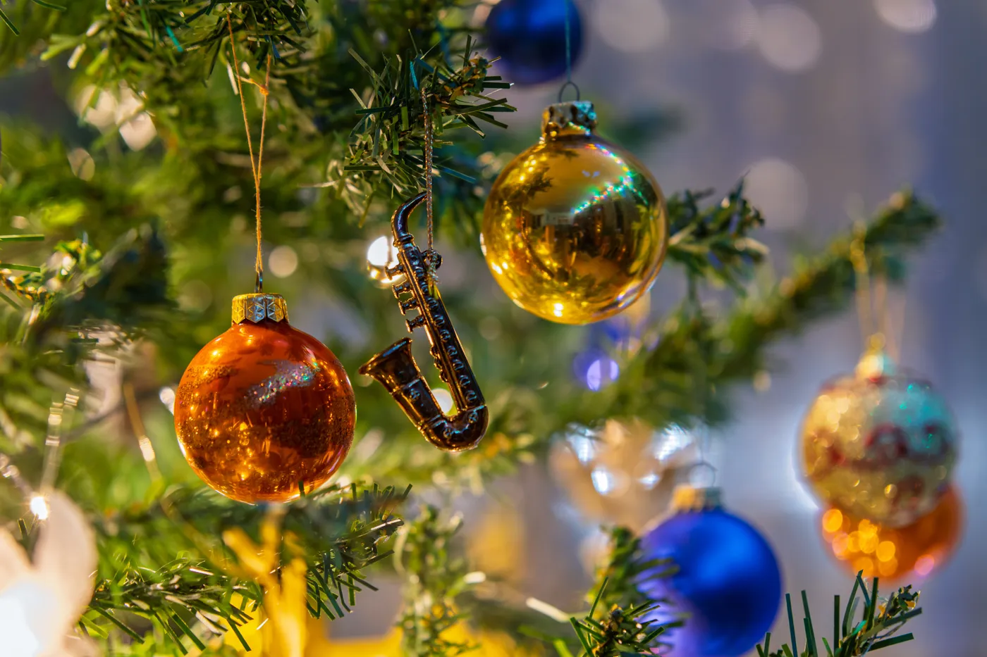 Vibrant Christmas ornaments and saxophone decoration hang on a festive tree, capturing holiday cheer.