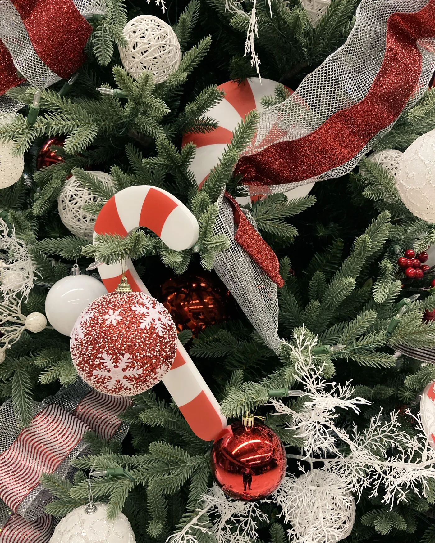 Vibrant Christmas tree adorned with candy canes, red baubles, and festive ribbons.